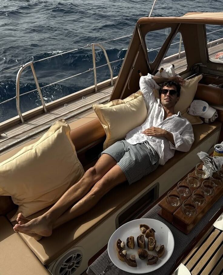 Man lounging on a yacht reading, sea breeze